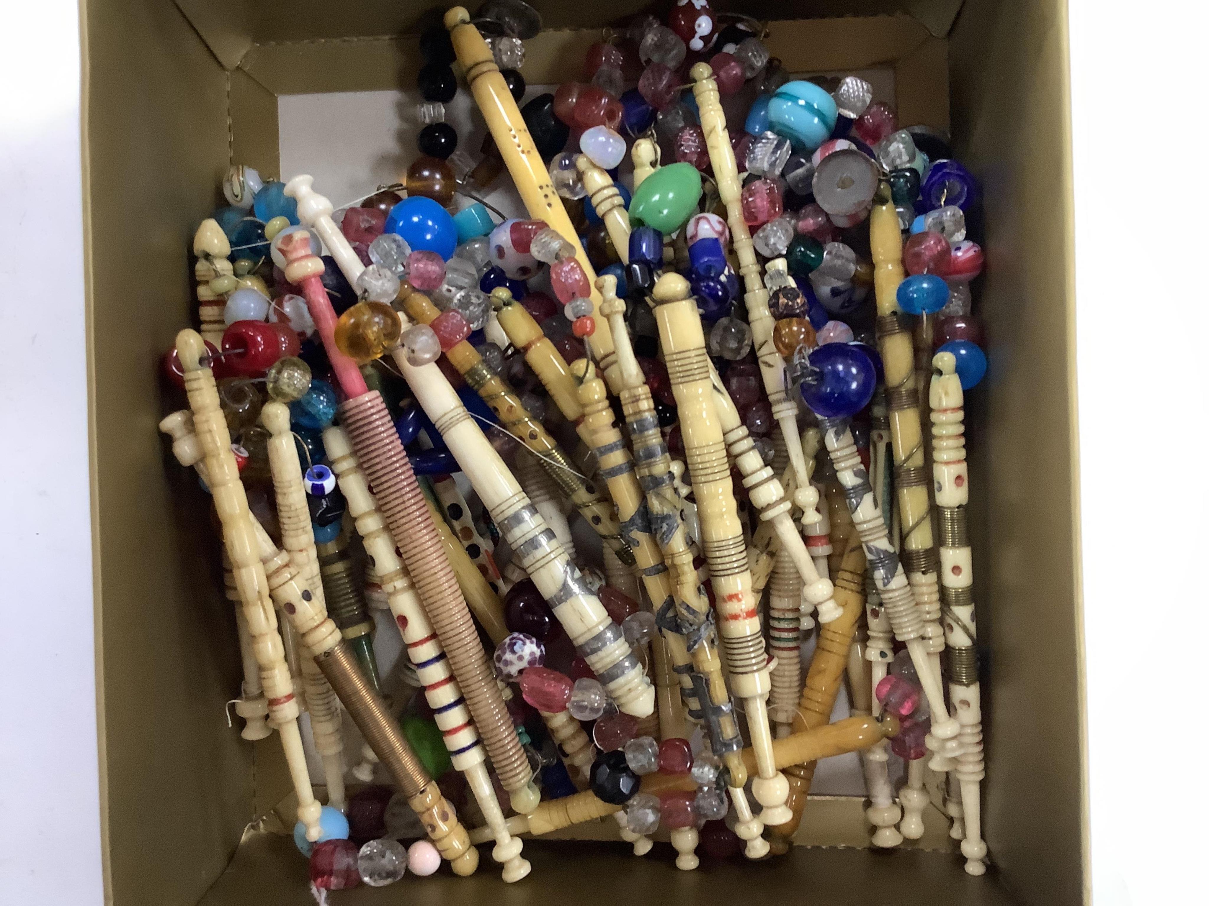A collection of mostly 19th and 20th century ornate bone lace making bobbins, with coloured beaded ends, together with a similar smaller selection of wooden bobbins. Condition - good